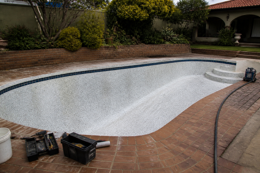 Empty drained pool mid-renovation with a cleaned marbelite shell