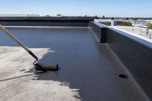 Rubberised black waterproofing membrane being rolled onto a concrete roof