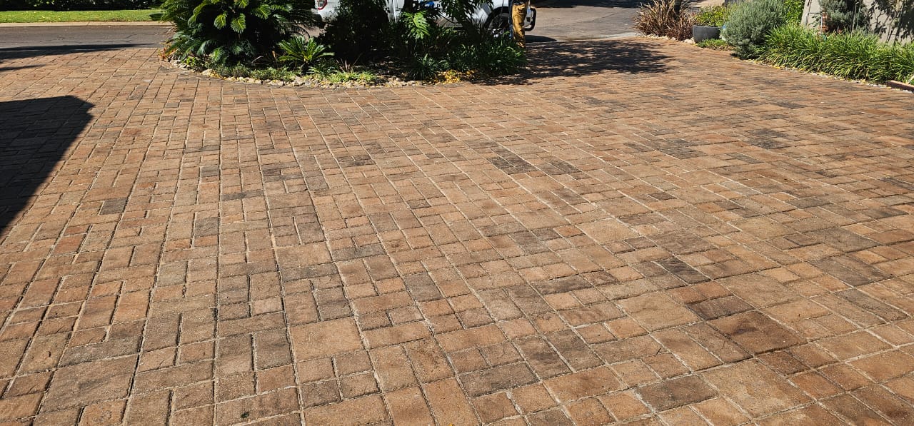 Completed brick paver driveway sealed with Rhinoluxe Stone Sealer with garden landscaping