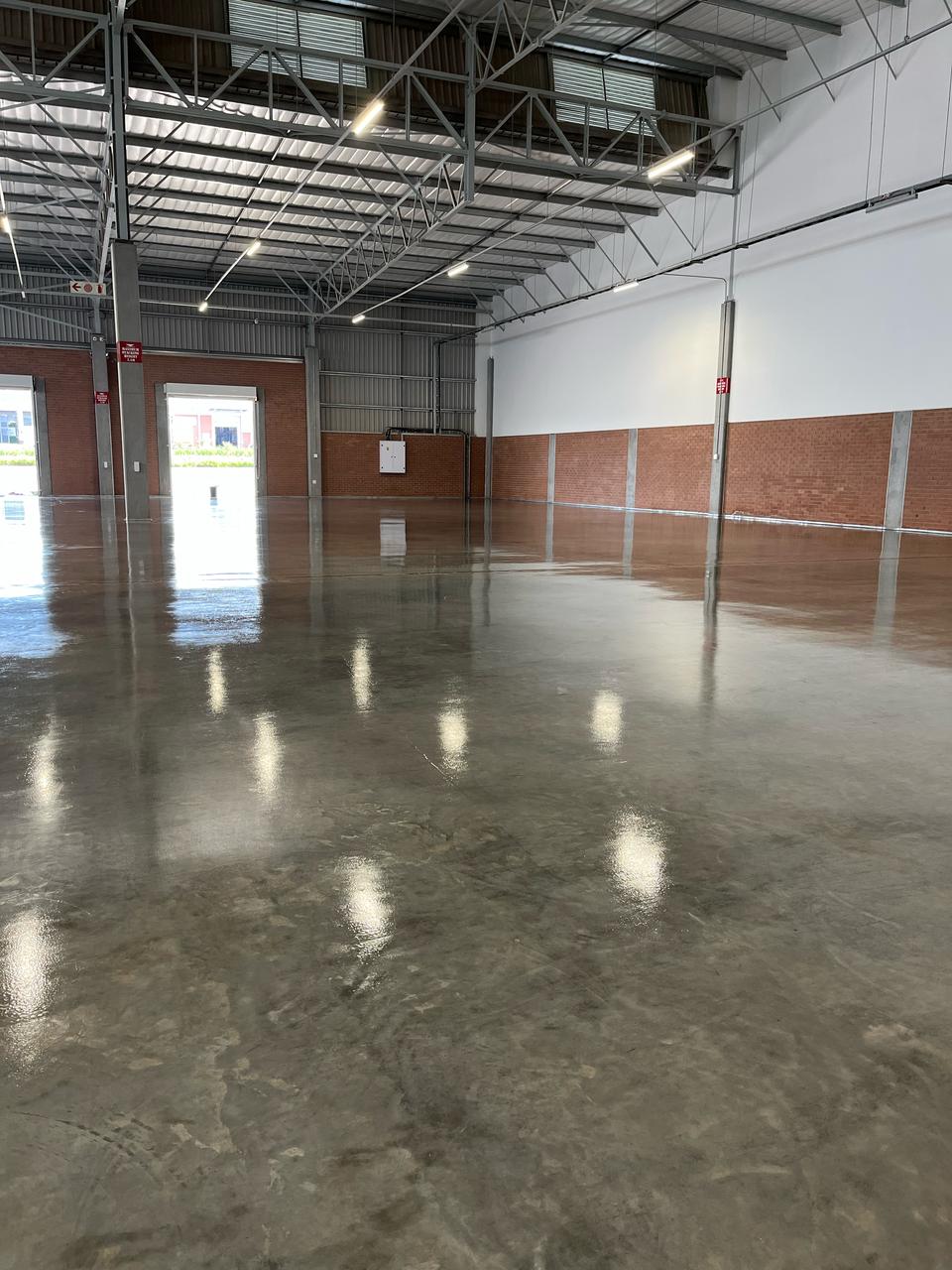 Wide-angle view of warehouse with Rhinoluxe Stone Sealer applied to entire concrete floor