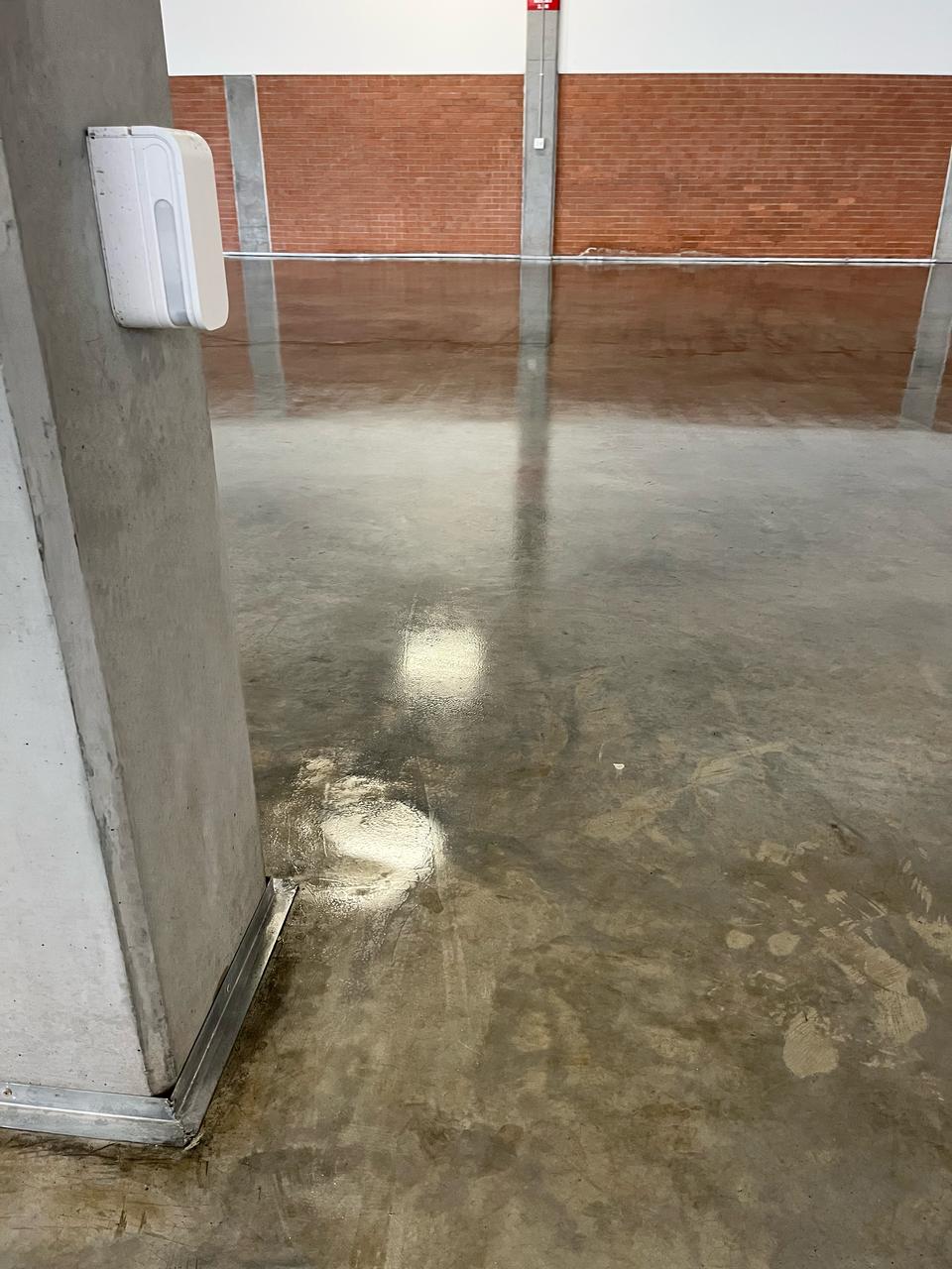 Industrial warehouse floor with stone sealer high-gloss finish reflecting overhead lighting