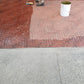Applying Rhinoluxe Stone Sealer with roller to red clay paver walkway at shopping mall entrance
