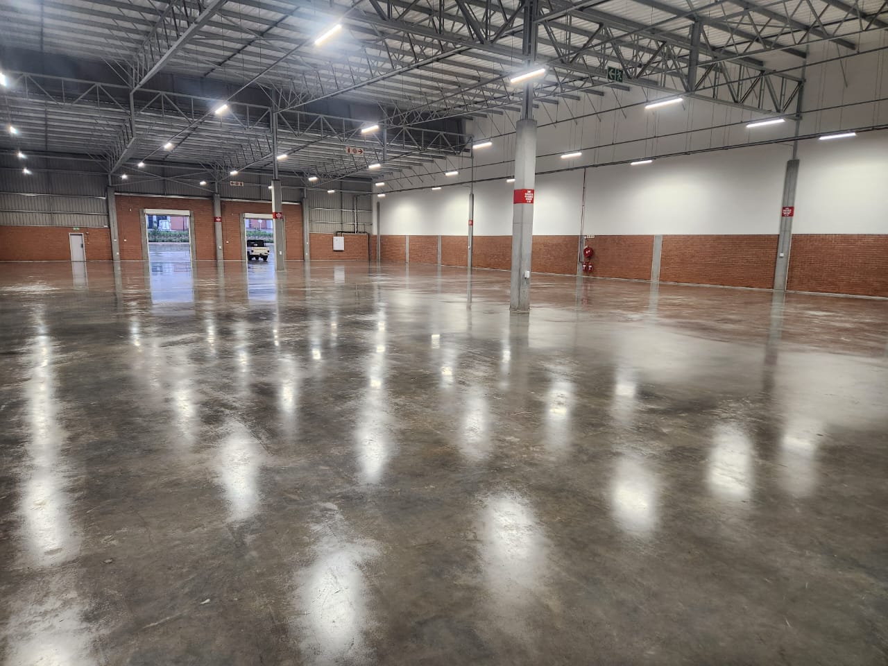 Large warehouse concrete floor sealed with Rhinoluxe Stone Sealer showing high-gloss reflective finish