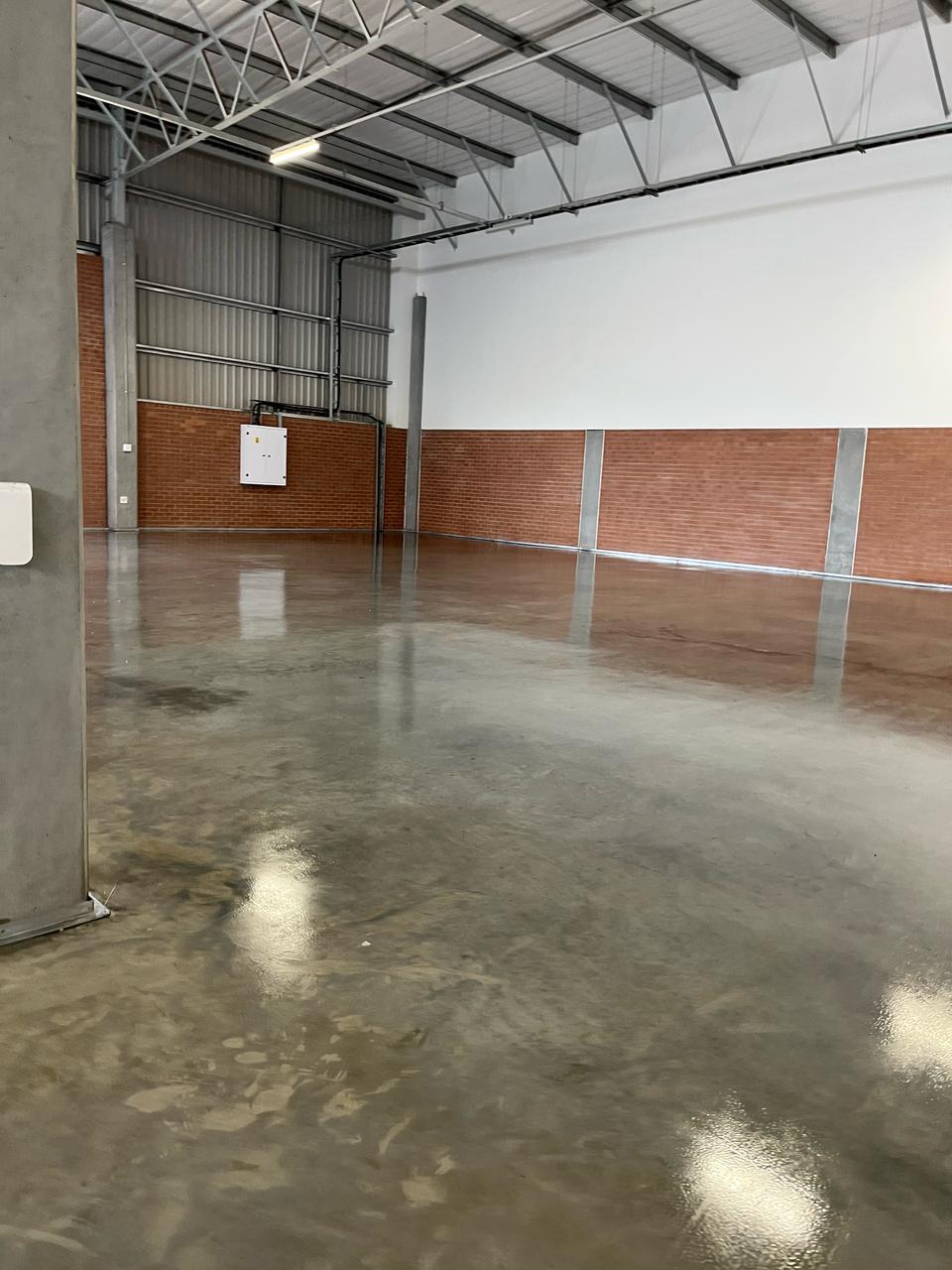 Sealed warehouse concrete floor with mirror-like gloss finish and brick accent walls